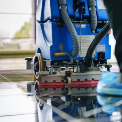 Worker cleaning office lobby floor with machine